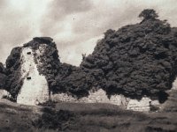 Le château (vers 1970) avant la restauratio  L'image en noir et blanc montre l'état des vestiges à une époque où la végétation et le lierre recouvraient massivement les structures en pierre, avant les campagnes contemporaines de stabilisation et de restauration menées par la commune et les associations locales.